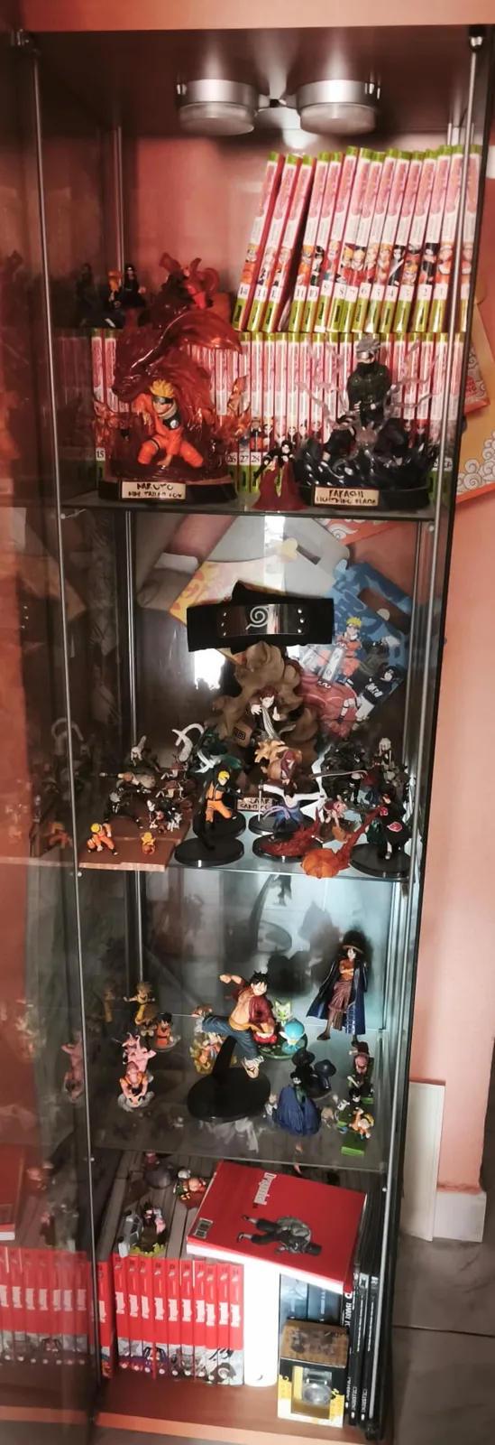 Vitrina de cristal con figuras y manga de Naruto, One Piece y Dragon Ball
